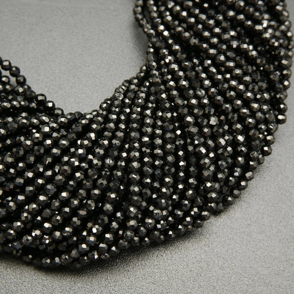 Faceted round black spinel beads on a string.